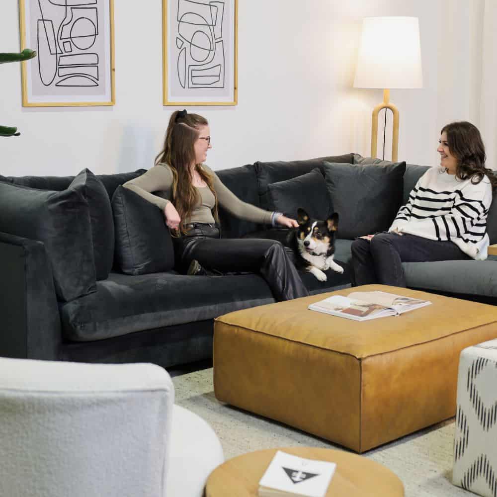 Two women and a corgi on a Sectional